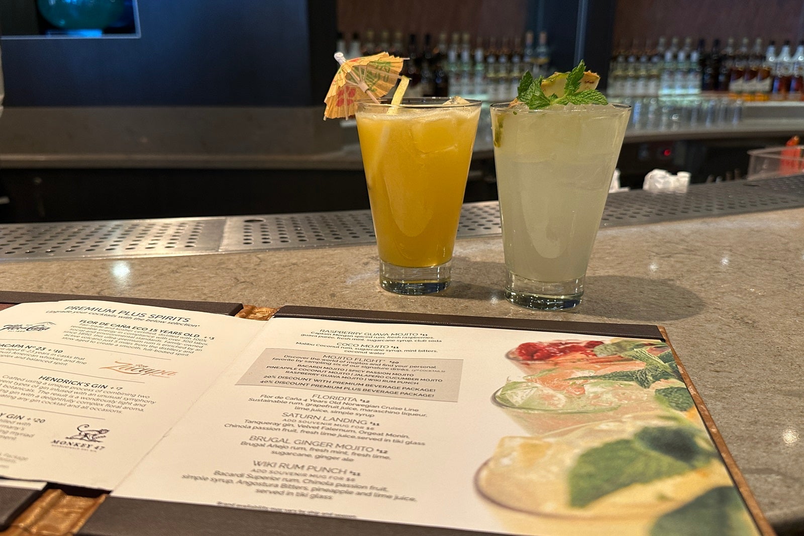 Two fruity cocktails next to a drink menu