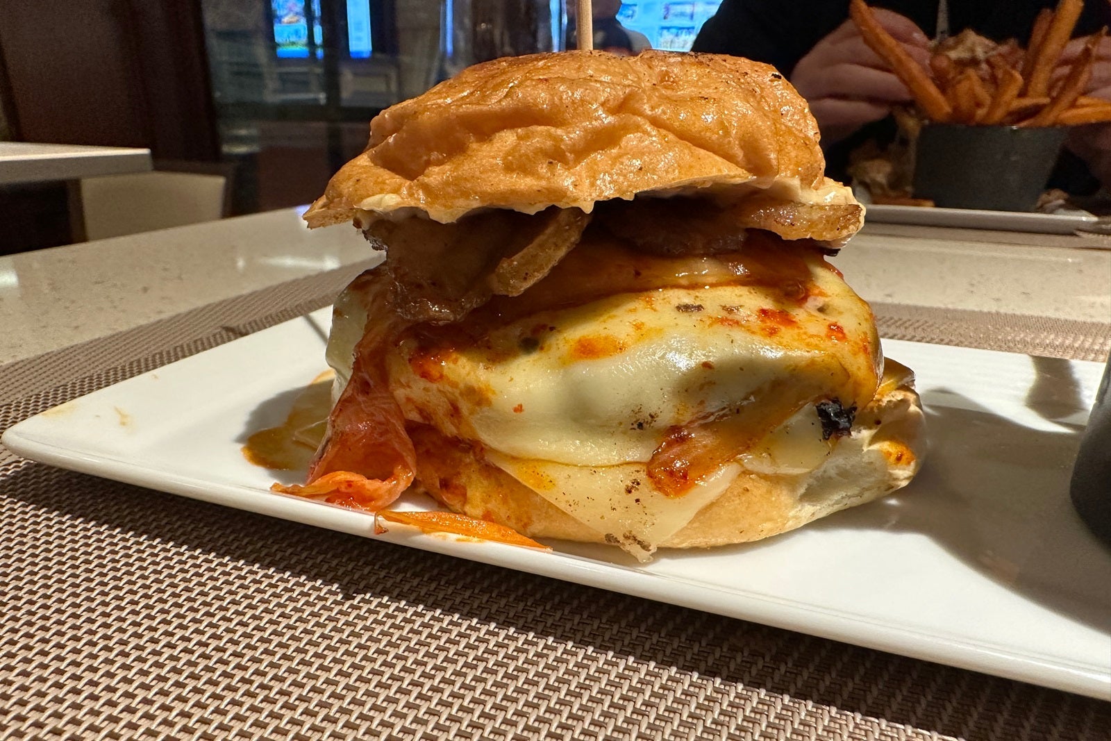 A cheeseburger with cheese melting down the side