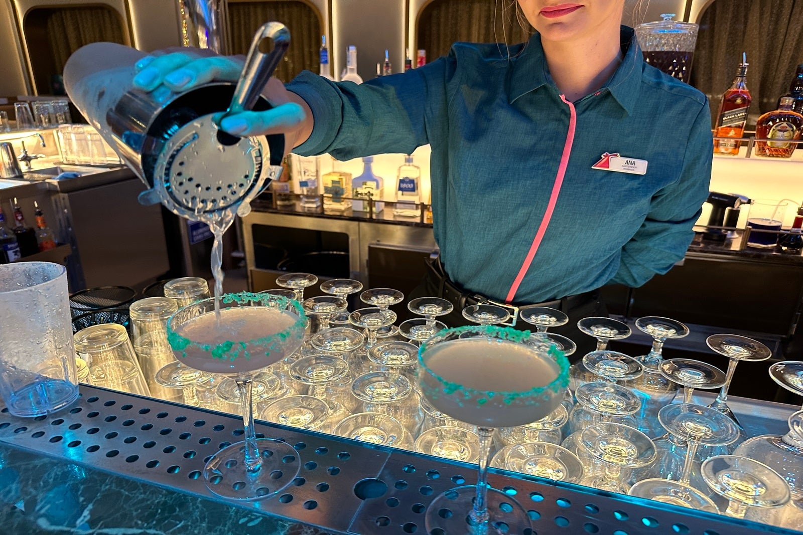 A bartender pouring a cocktail from a shaker