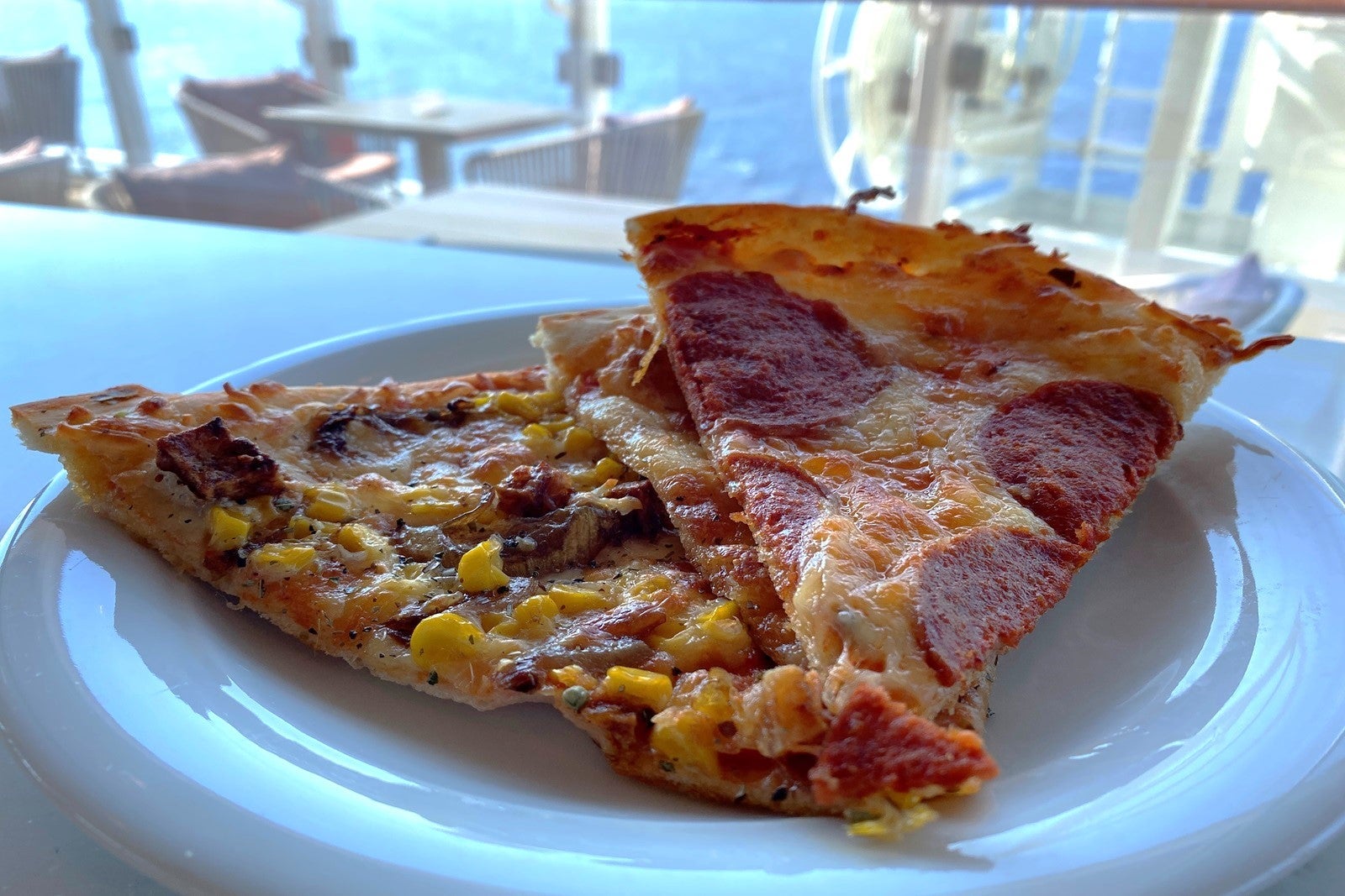 Three slices of pizza on a plate by a window