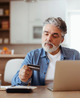 Man using a laptop and holding a credit card