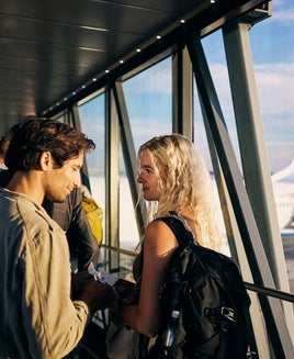Young adult couple embarking on a weekend vacation, boarding the plane on the runway.