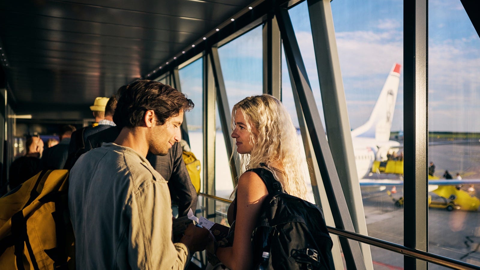 Young adult couple embarking on a weekend vacation, boarding the plane on the runway.