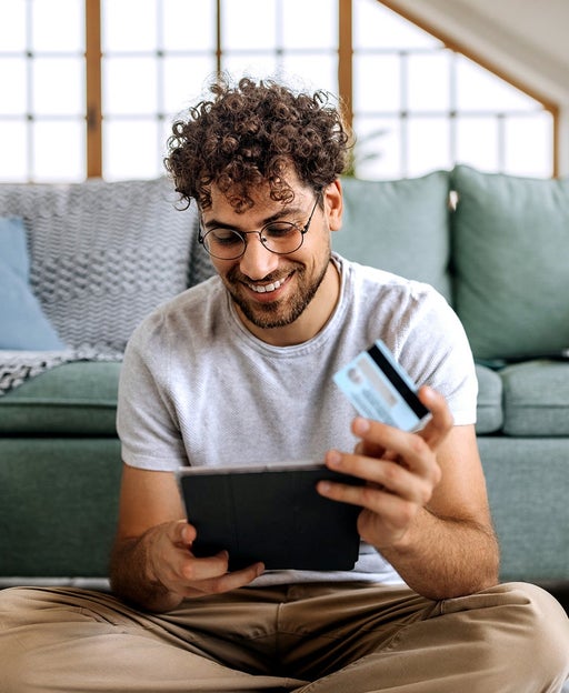 Young casually clothed man shopping online while sitting on a floor at home