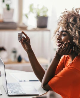 Woman looking at credit card while using a laptop