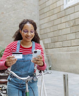 Person looking at a credit card and phone while on a bike