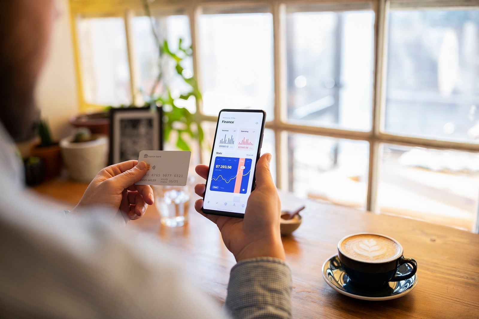 A person holding holding a credit card while looking at a bank account
