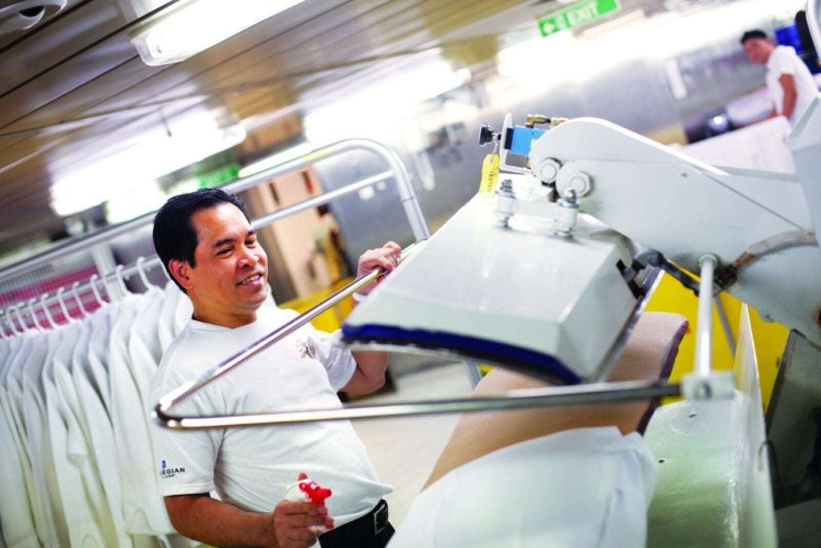 Crew member pressing laundry on a cruise ship