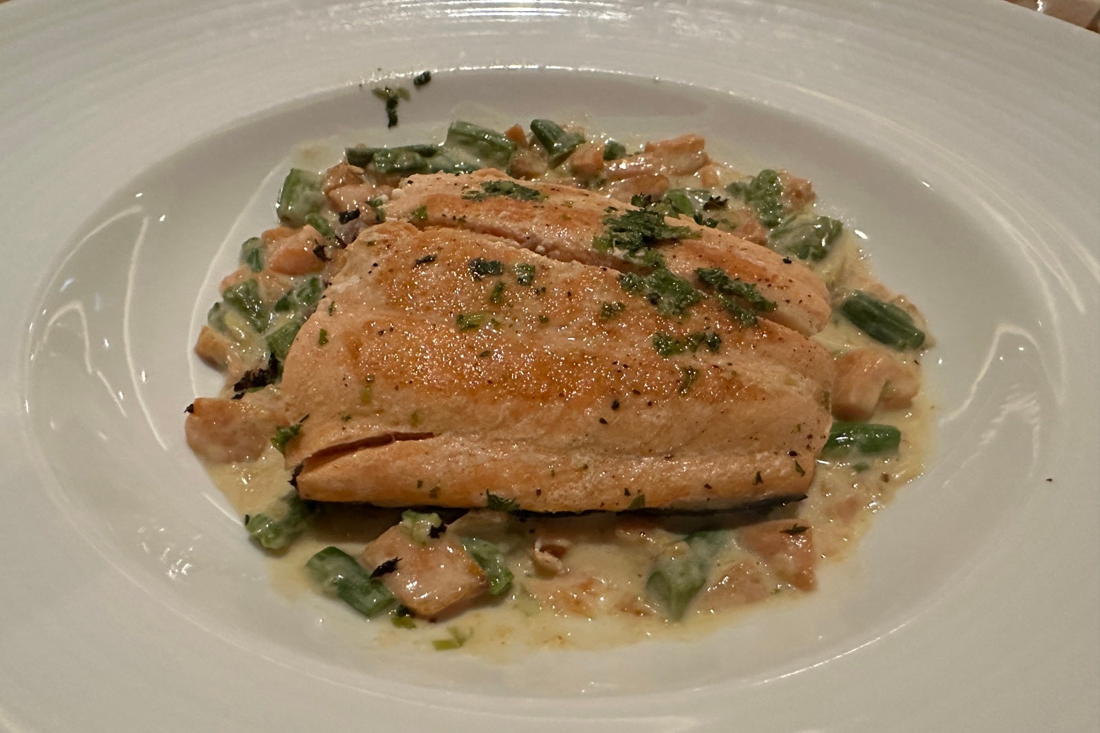 A white plate with salmon and greens