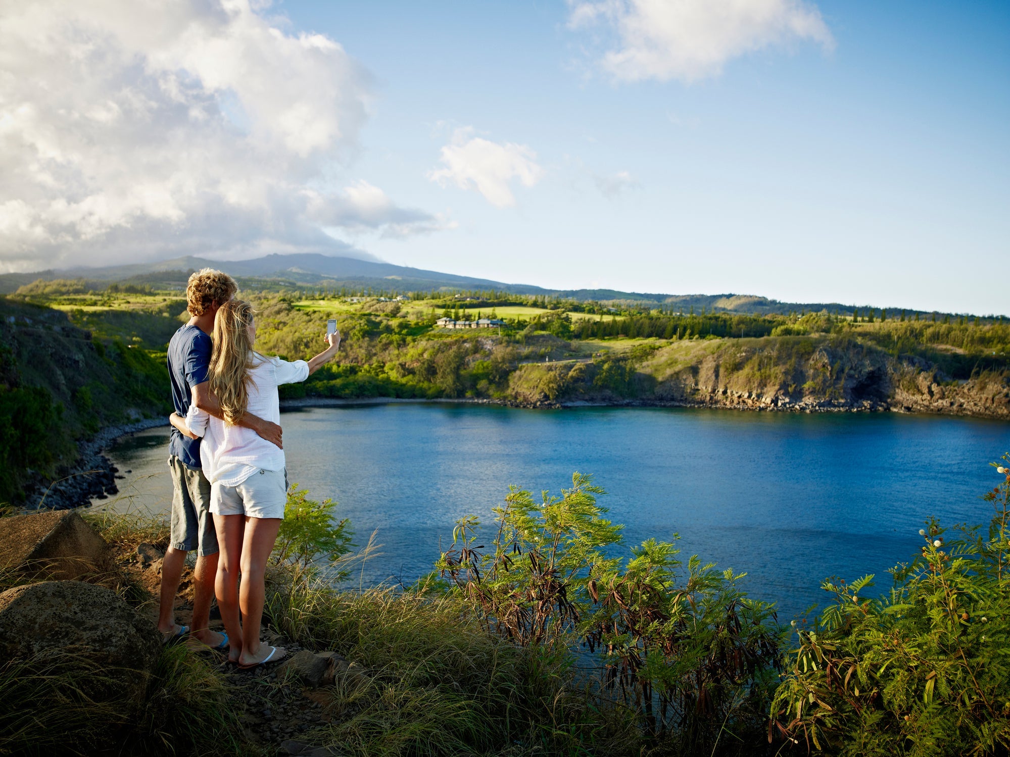 Two people taking a selfie on a cliff in Maui, Hawaii