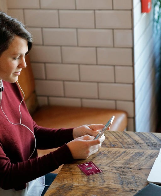 woman sitting at a table looking at her phone