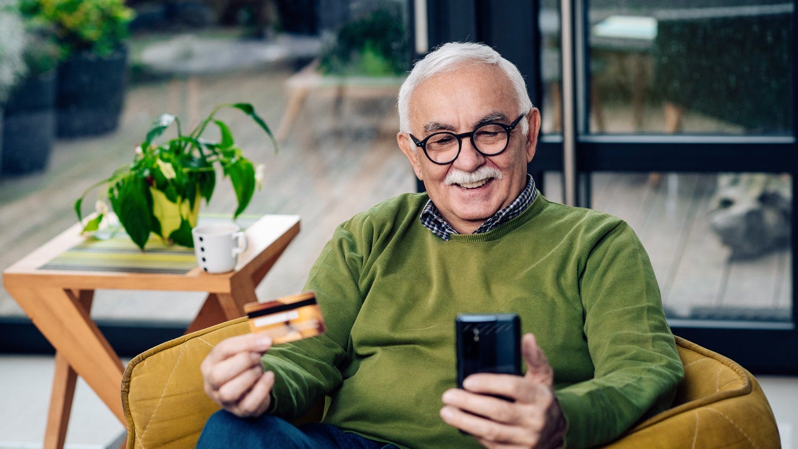 Portrait of a senior man using a credit card for online shopping at home