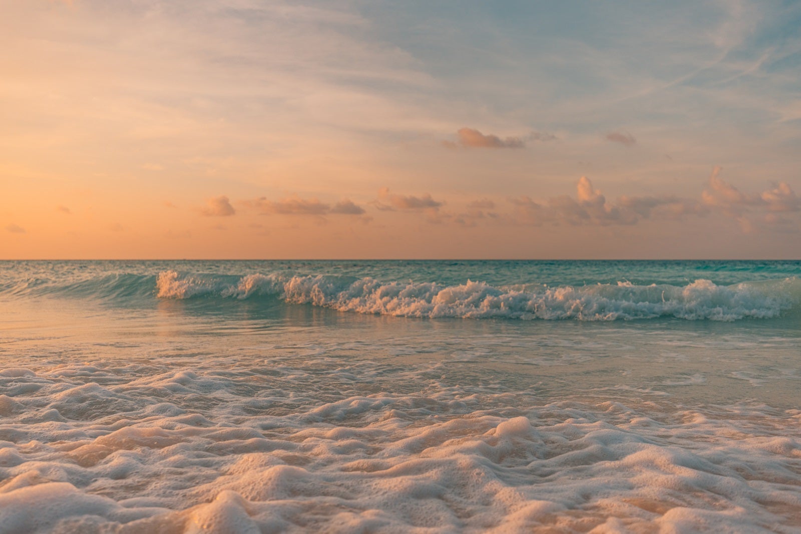 A calm beach with waves and surf at sunset