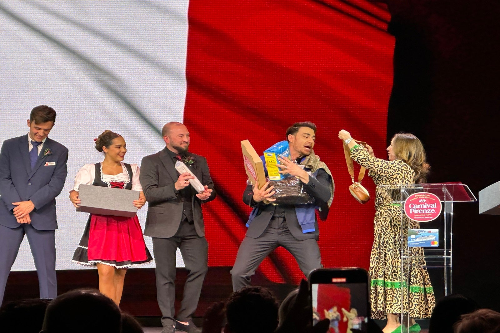 Actor Jonathan Bennett on a stage with people handing him Italian-themed items