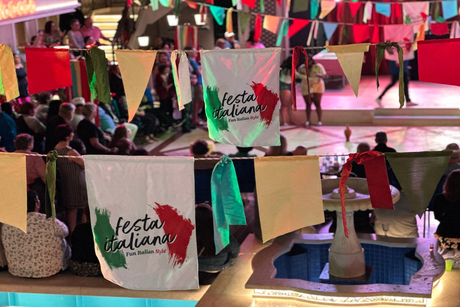 Red, white and green flags hanging in the air over the Carnival Firenze's pool deck