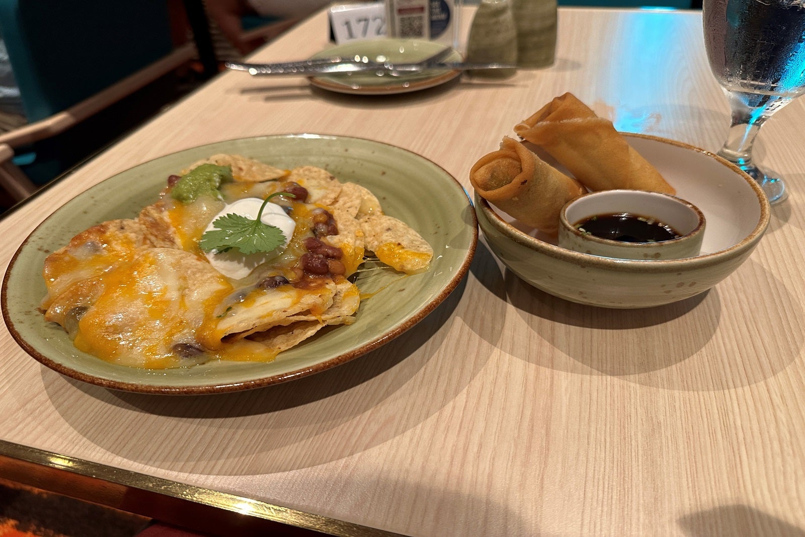 Plates of nachos and spring rolls sitting on a table
