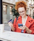 Woman sitting outside holding two credit cards