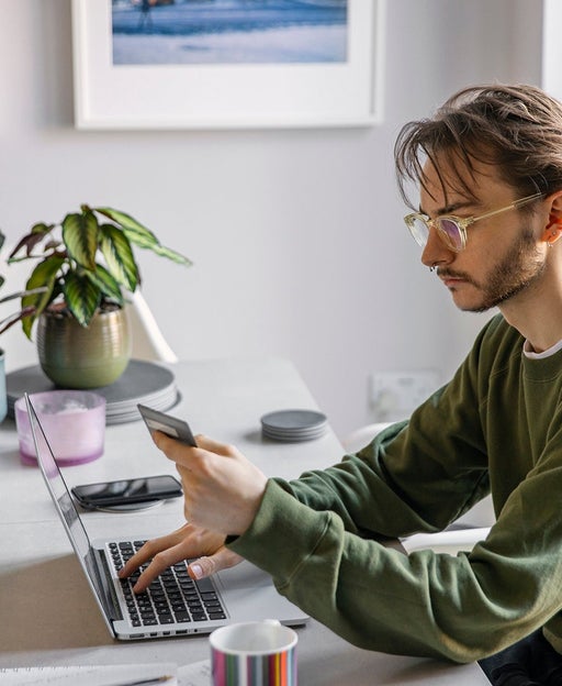 A person using a computer while holding a credit card
