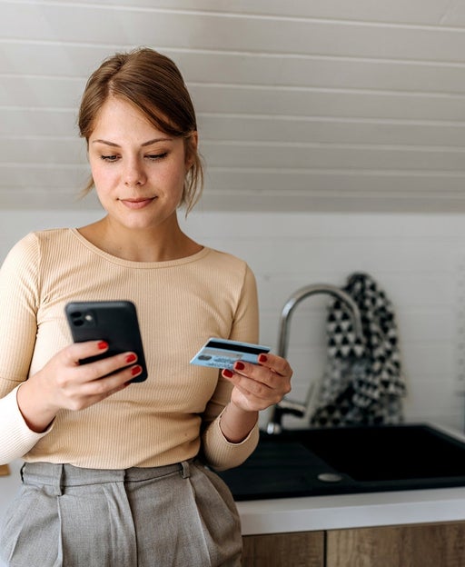 Young casually clothed woman online shopping from her domestic kitchen