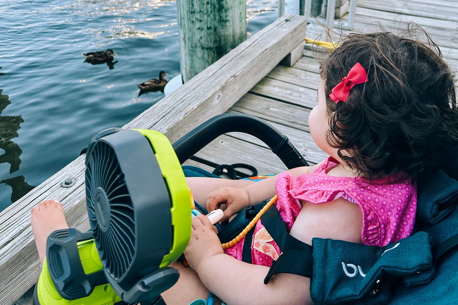A toddler sitting on a dock by the water