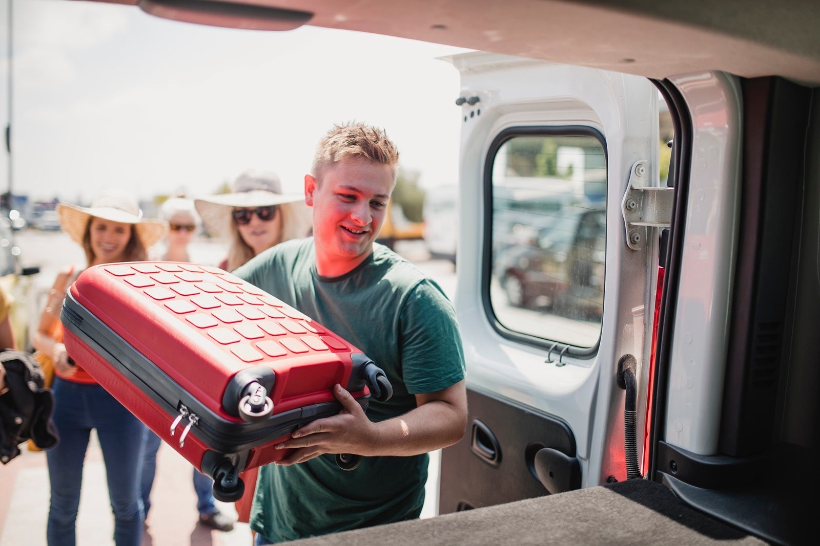 Shuttle driver loading luggage into the back of a van