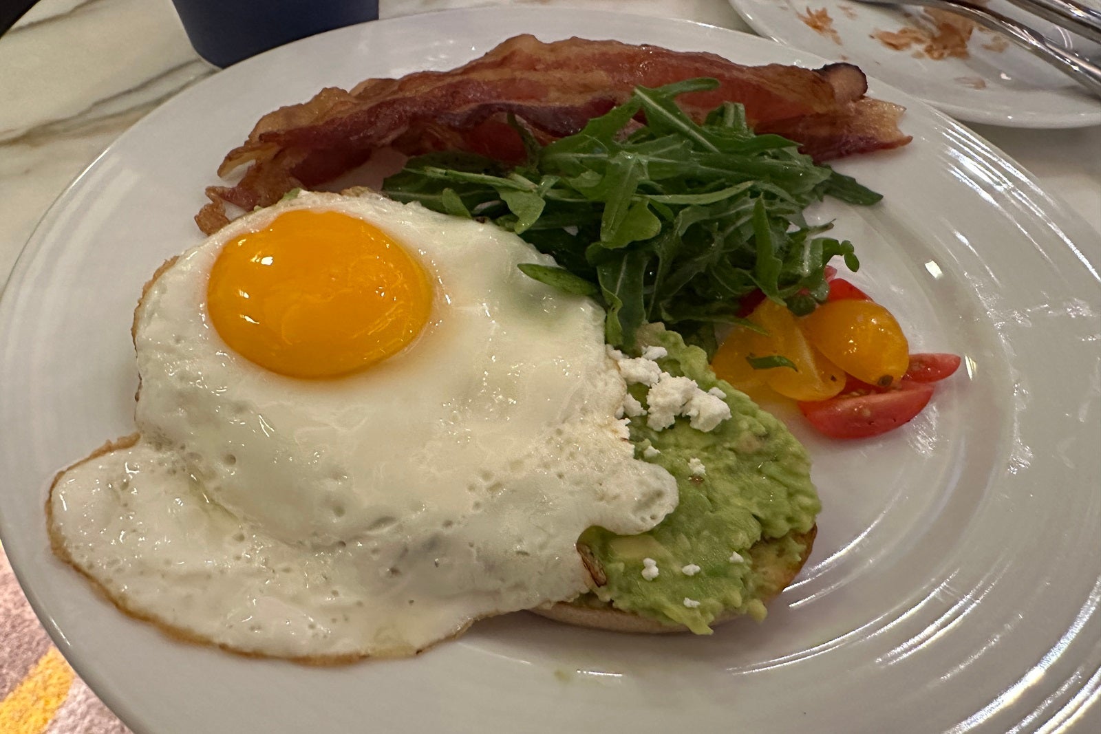 Avocado toast on a plate with bacon and an egg
