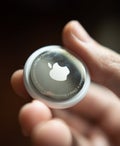 A person holding an Apple AirTag in their hand