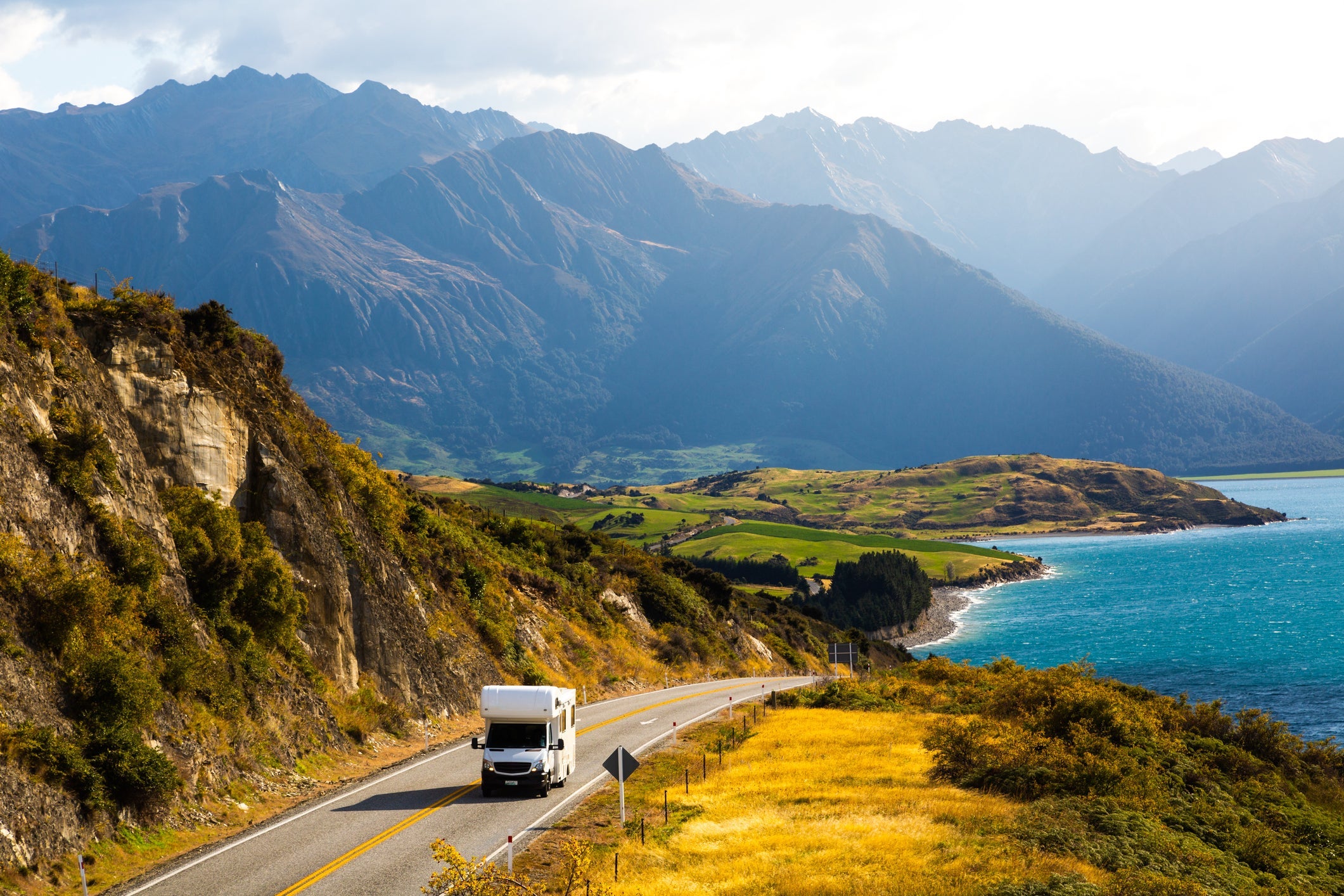 A camper van driving by Lake Hawea, New Zealand.