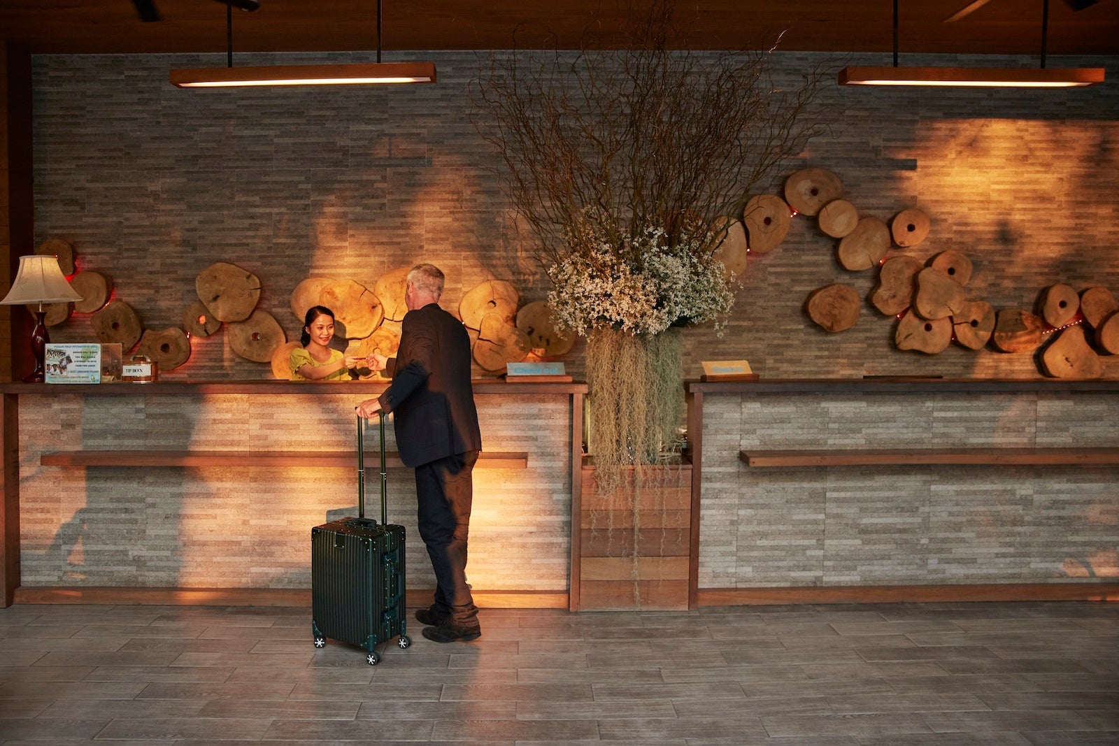 A person with a suitcase at the front desk of a hotel