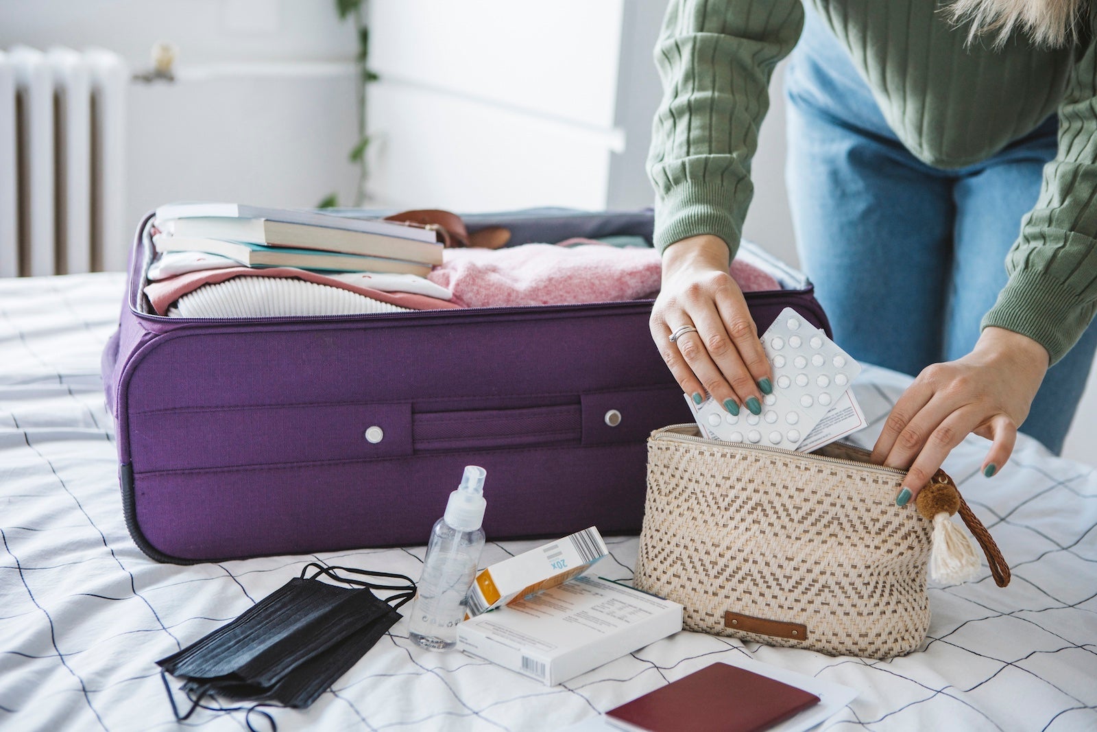 A person packing pills and hand sanitizer into their bag.