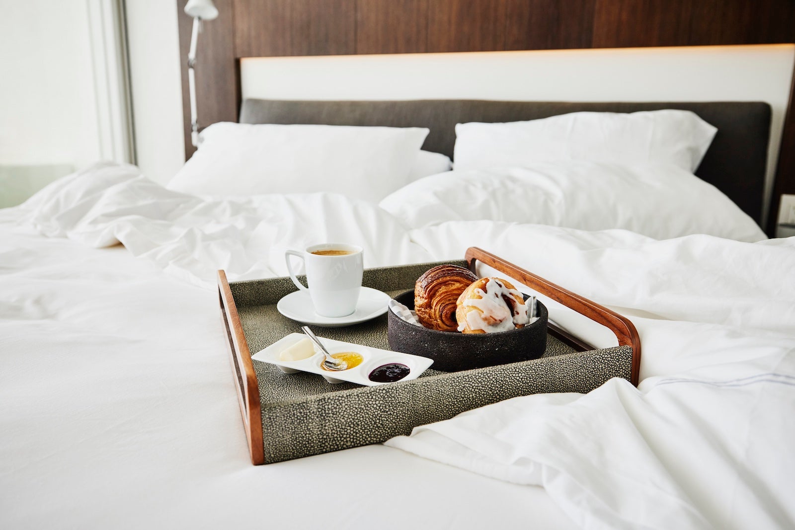 A tray table of pastries and coffee on a bed