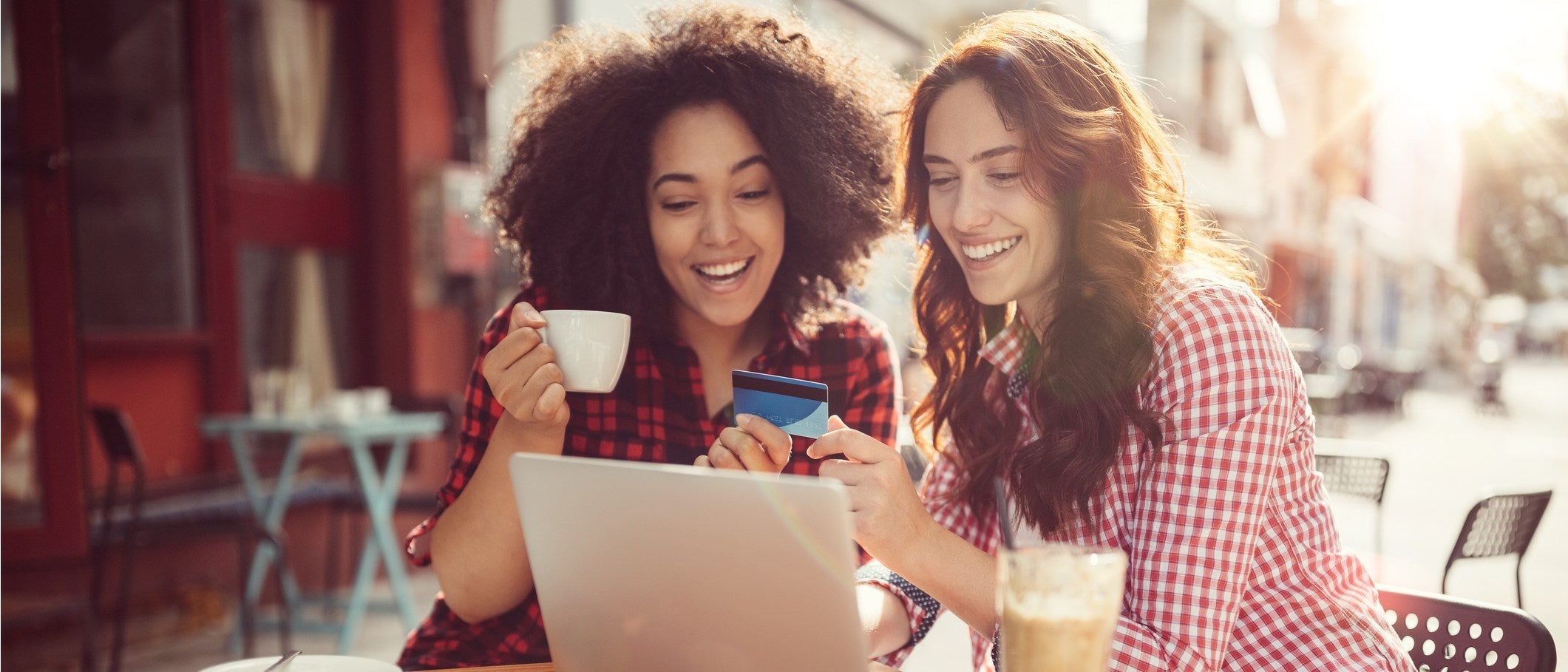 Two women having coffee and smiling at a credit card
