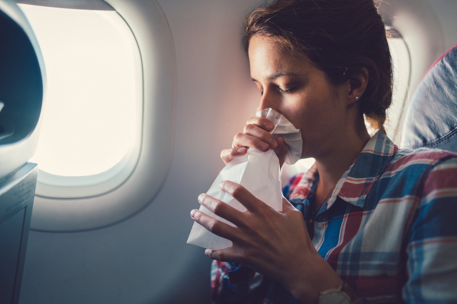 A person on an airplane breathing into a paper bag.