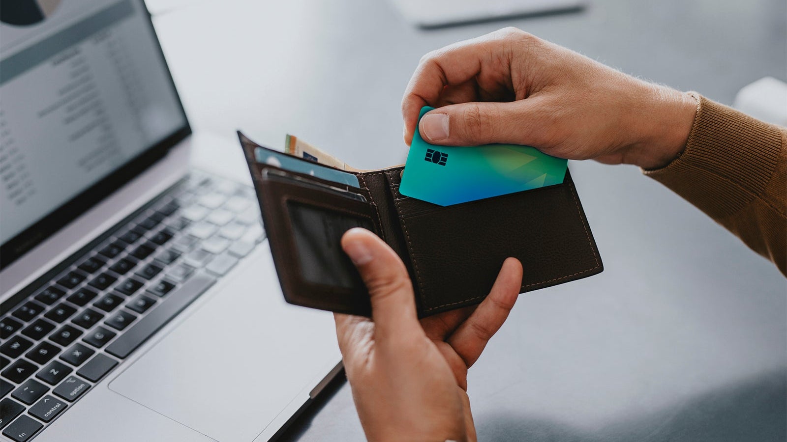 Hands of a Man Taking his Credit Card out of His Wallet to make on Online Order on his Laptop Computer