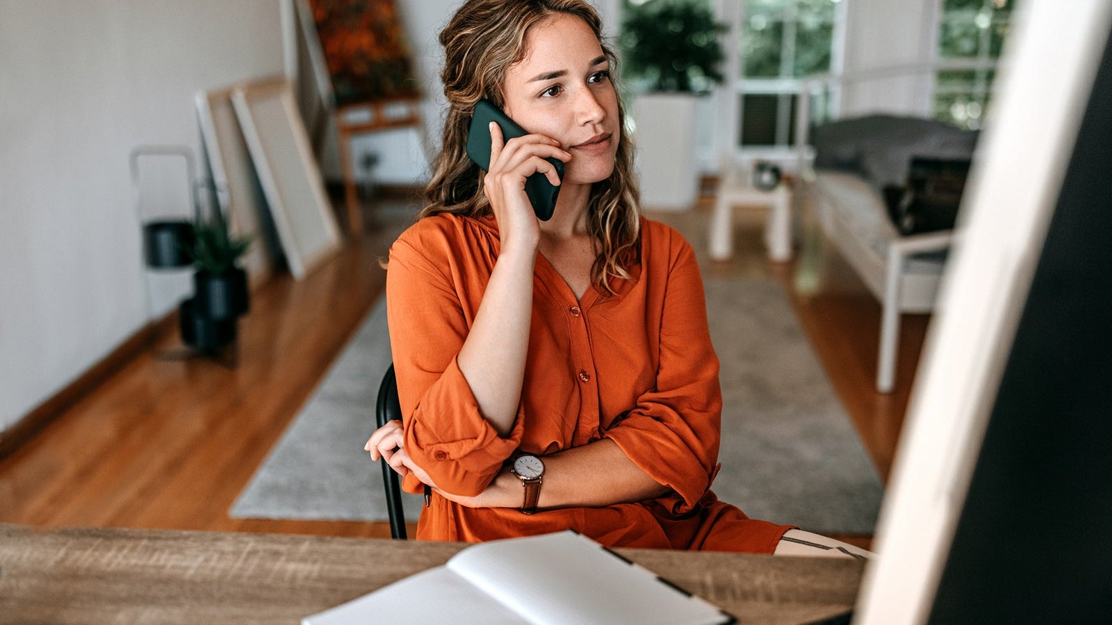 Young woman talking on smart phone at home office
