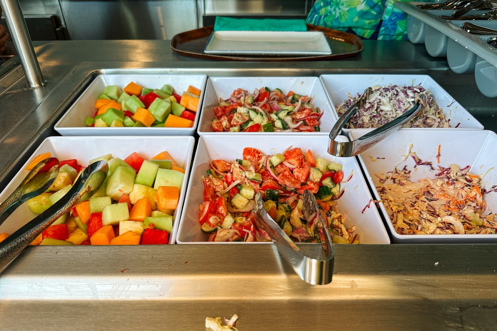 Fruit, salads and other sides in bowls with tongs