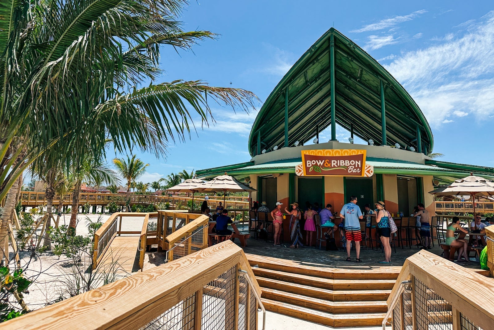 A beach bar with a peaked roof and stairs to the beach