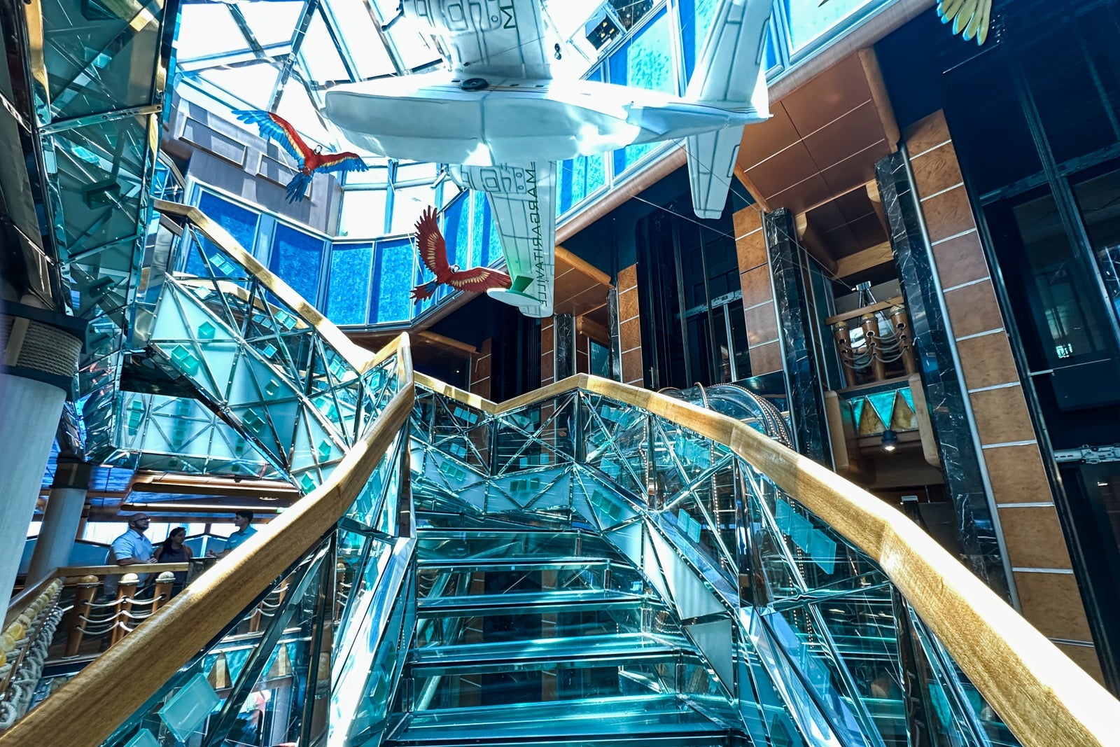 A see-through staircase on a cruise ship with a large model plane hanging above it