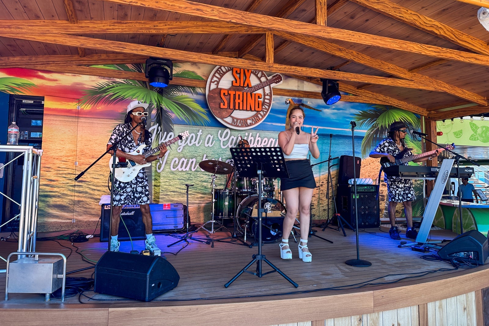 A musical group performs on a pool deck stage on a cruise ship
