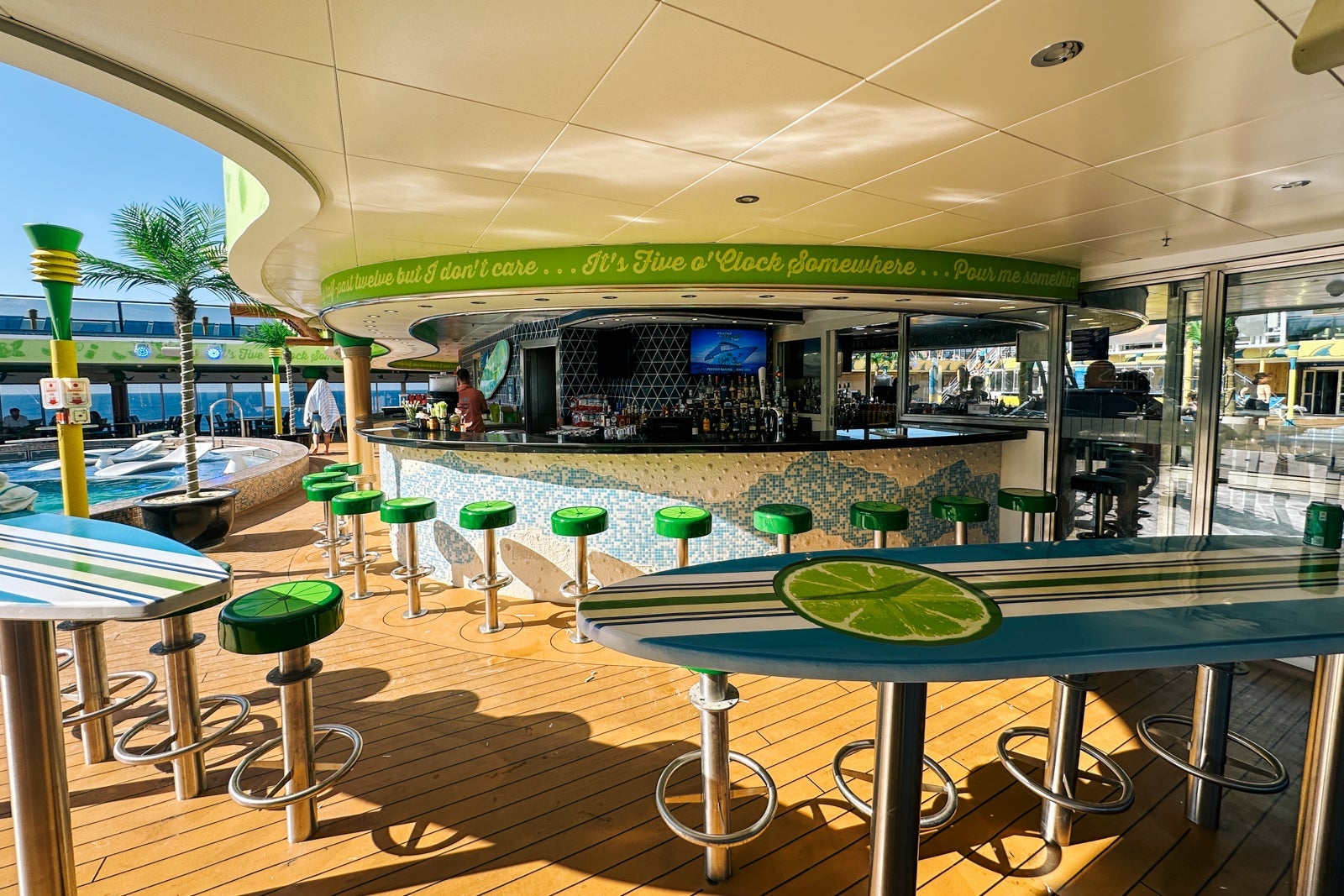 A covered pool deck bar on a cruise ship with barstools that look like limes