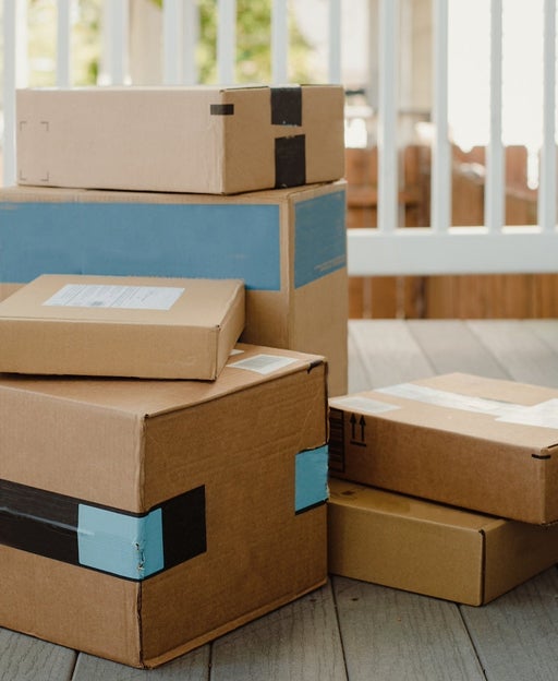 A stack of Amazon packages on a porch