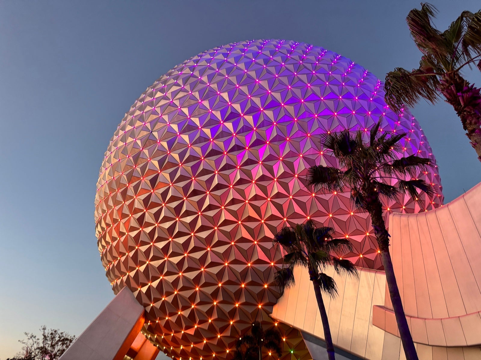 A giant sphere, resembling a golfball, colored purple and orange, housing the Spaceship Earth ride at Epcot at Wald Disney World Resort