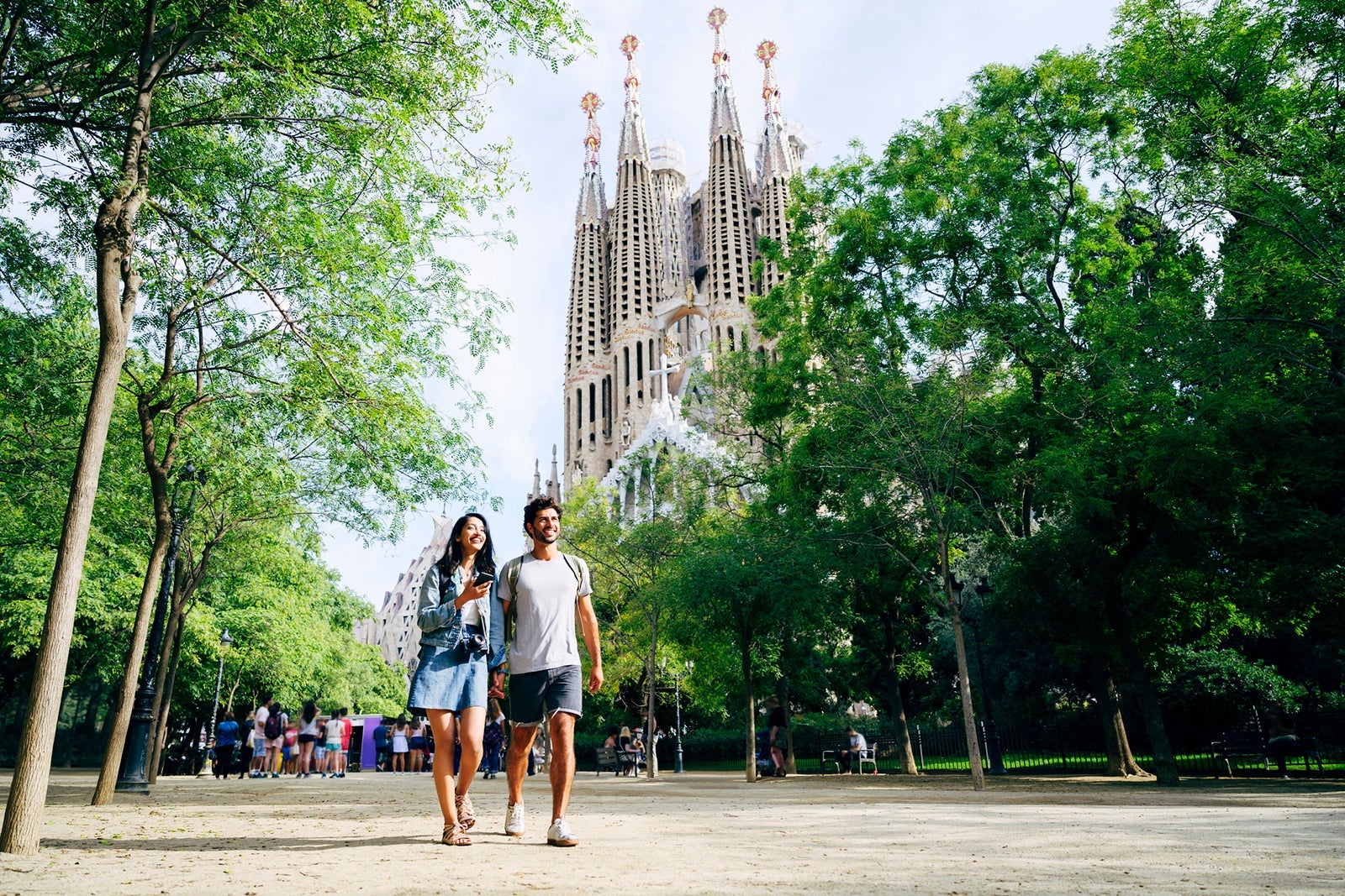 A couple walking hand in hand in front of Barcelona's La Sagrada Familia