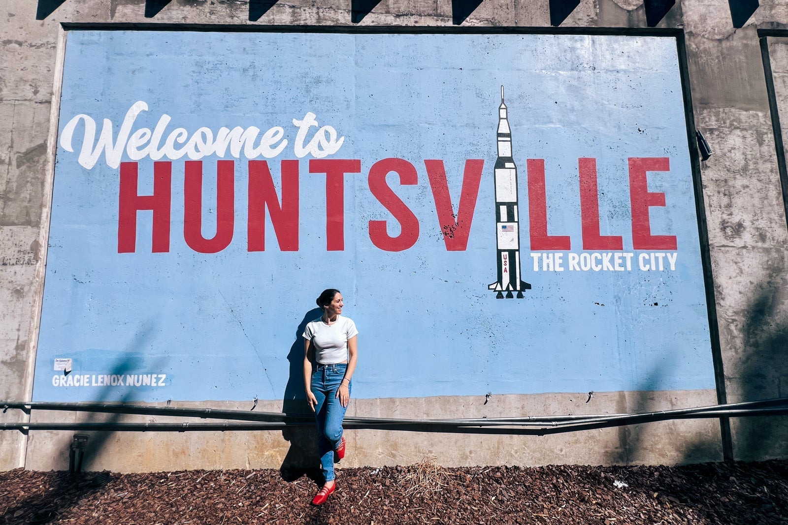 woman stands in front of Huntsville Alabama sign