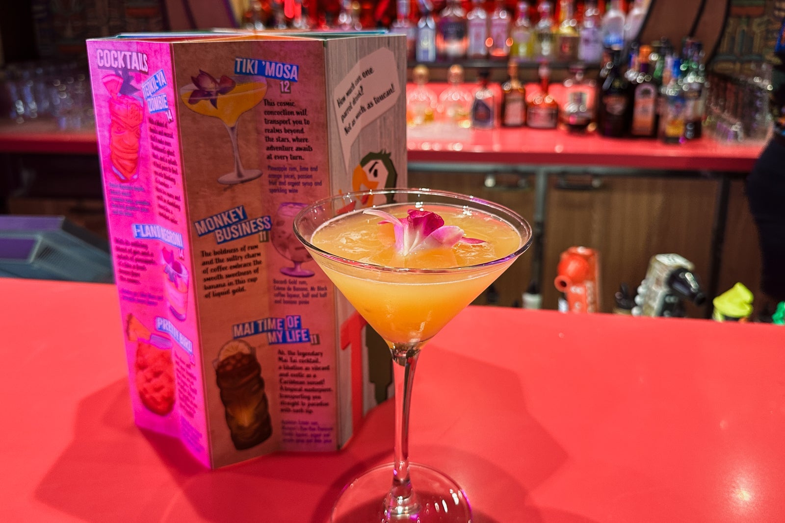 A cocktail in a martini glass next to a menu at a bar