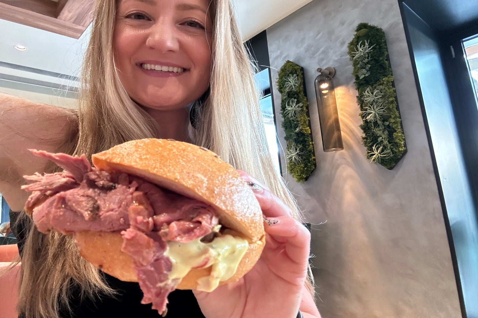 A woman holding a beef on weck sandwich