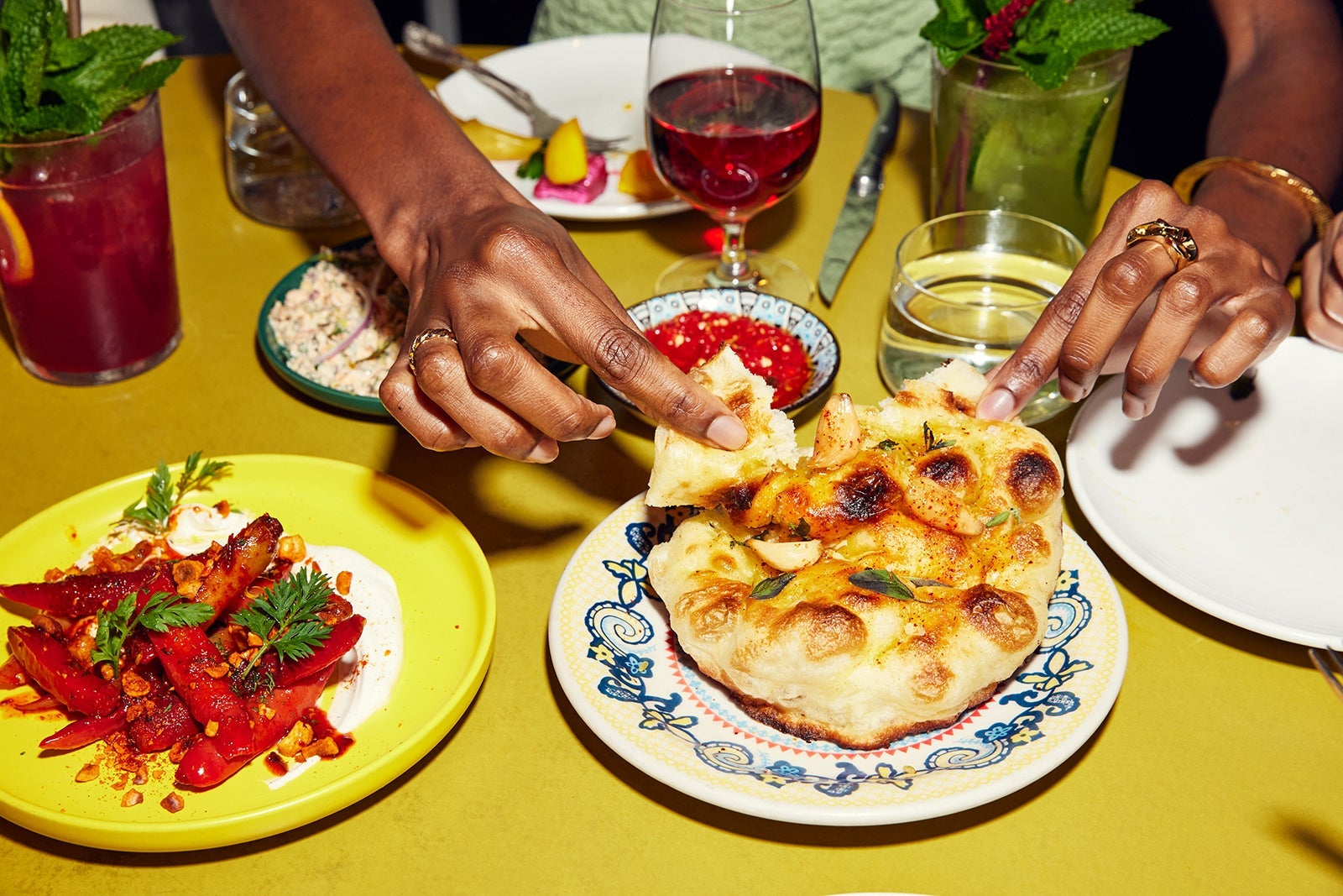 Hands reaching into a table of food