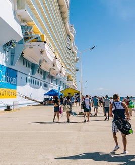 Cruise passengers walking along a pier back to their cruise ship
