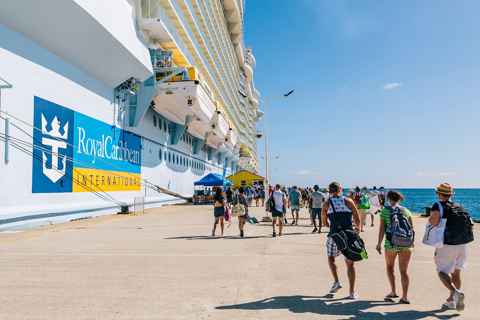 Cruise passengers walking along a pier back to their cruise ship