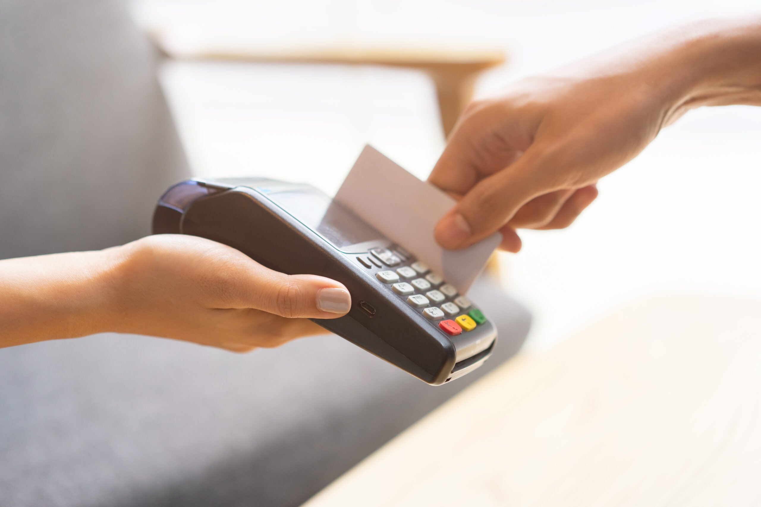 close up waitress worker hand giving an electronic banking money machine for receiving purchase from customer's credit card in restaurant shop , business and technology of contactless payment concept